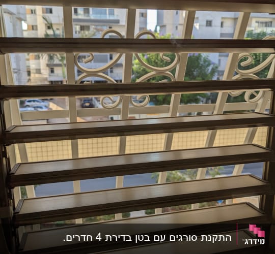 סורג ברזל לבן דקורטיבי בחלון הנראה מבעד לשלבי תריס